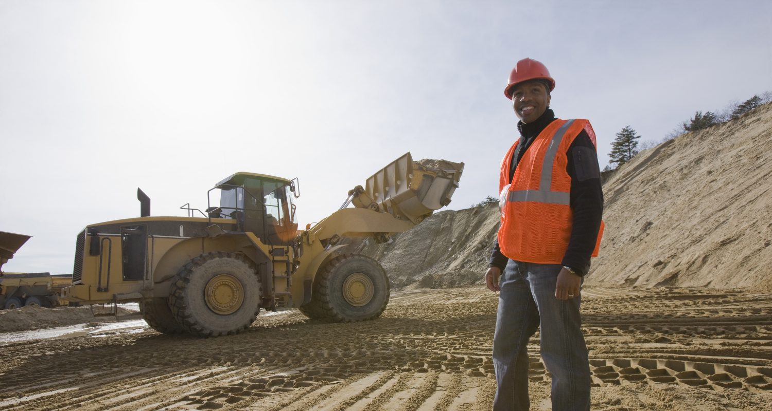 Engineer at a construction site with a front-end loader in the background